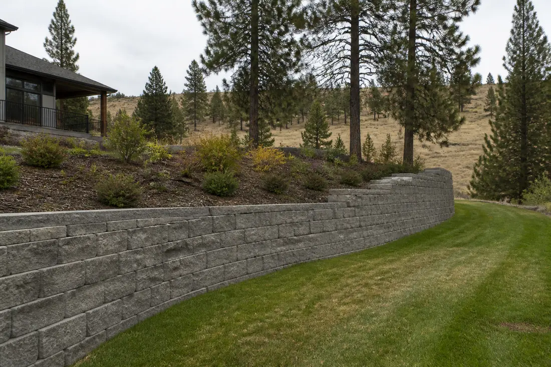 A segmental block retaining wall holding a slope above a yard