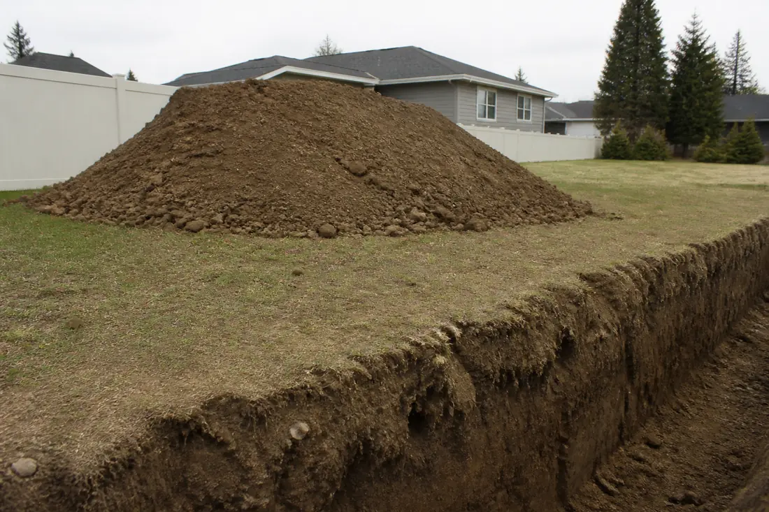 A mound of excavated soil placed back from the edge of an open cut